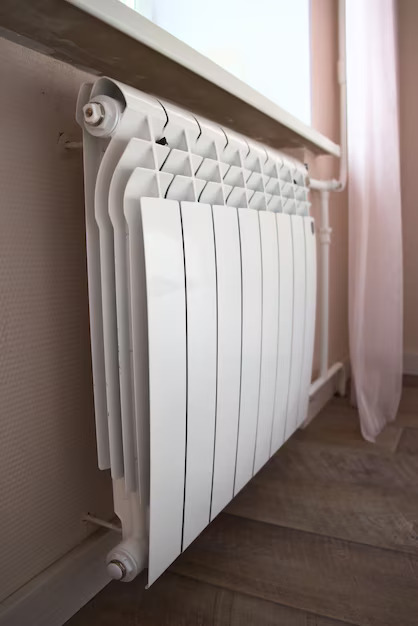 Radiateur blanc moderne installé par alamo-sarl sous une fenêtre dans un salon lumineux à Limoux,
