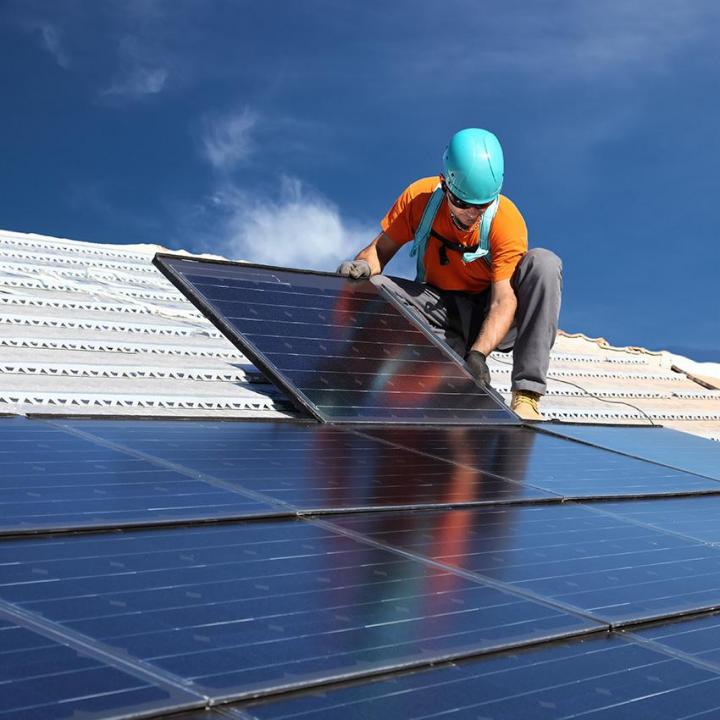 technicien alamo-sarl installant un panneau solaire sur toit en métal à Limoux sous un ciel ensoleillé,