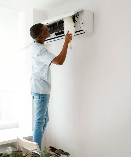 Nettoyage climatiseur mural alamo-sarl Limoux alamo-sarl entretien climatiseur mural dans une maison à Limoux, homme nettoyant avec plumeau,